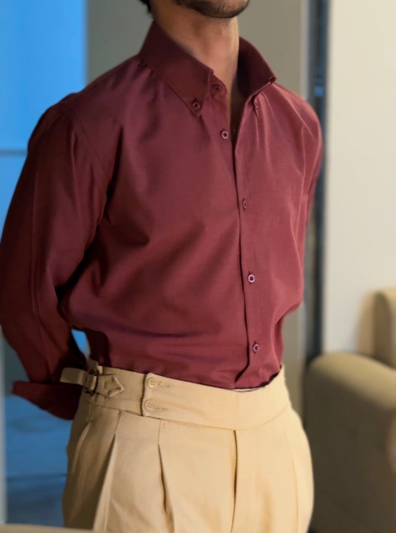 Person wearing a burgundy shirt and beige pants indoors